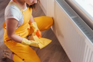 Housewife in yellow uniform works with window and surface cleaner indoors